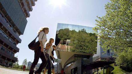 Drei Studentinnen gehen über den Campus einer Universität.