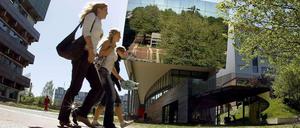 Drei Studentinnen gehen über den Campus einer Universität.