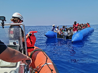 Eine Helferin des Rettungsschiffs "Eleonore" gibt Westen an Flüchtlinge auf einem Boot aus.