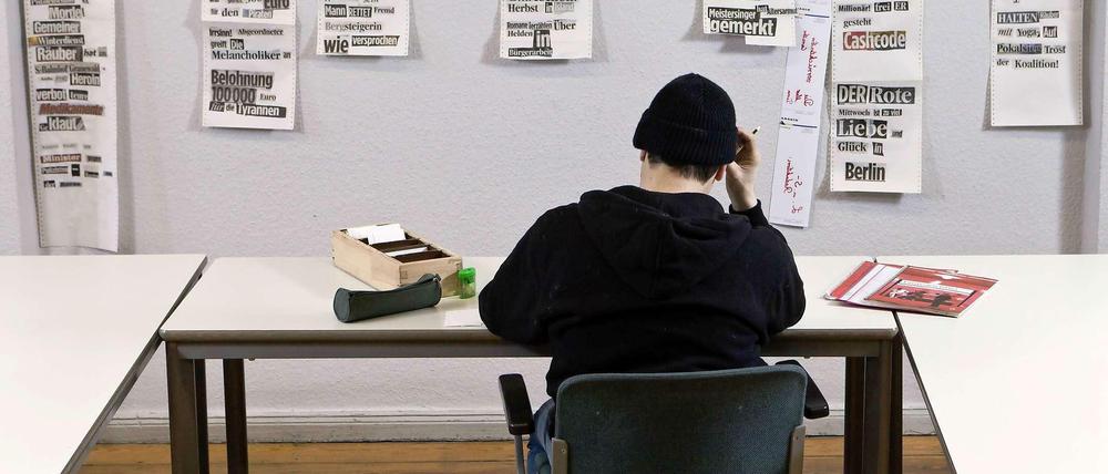 Ein junger Mann sitzt am einem Tisch und macht Schreibübung.