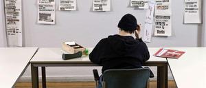 Ein junger Mann sitzt am einem Tisch und macht Schreibübung.