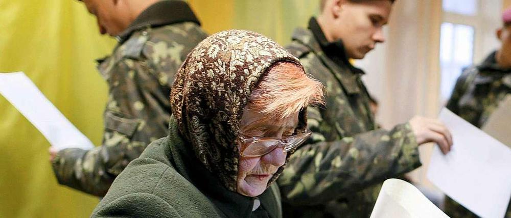 Eine Frau und mehrere Soldaten bei der Parlamentswahl in Kiew. 