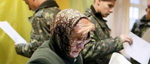 Eine Frau und mehrere Soldaten bei der Parlamentswahl in Kiew. 