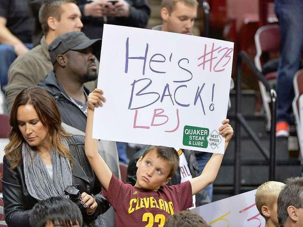 Ein junger Fan der Cleveland Cavaliers hält ein Schild mit der Aufschrift "He's back! #23 LBJ" in die Luft.