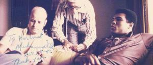 „To Hartmut.“ Unser Autor Hartmut Scherzer (links) sitzt mit Muhammad Ali in dessen Bungalow in Kinshasa. Dick Young von der „New York Post“ (M.) ist auch dabei. Später schrieb Ali eine Widmung auf das Foto.