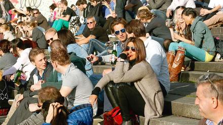Temperaturrekord. Bei 23 Grad sitzen Menschen in Düsseldorf auf den Stufen und genießen die Sonne.