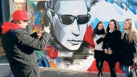 Popstar Putin. Junge Besucher einer Cartoon-Ausstellung vor einem Wandbild in Moskau. 