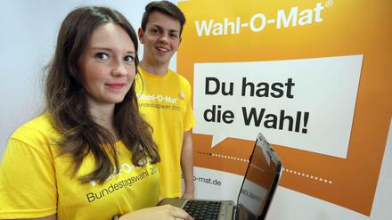 Zwei Jugendredakteure der Bundeszentrale für Politische Bildung stehen beim Start des interaktiven Online-Tools Wahl-O-Mat 2013 vor dem Logo.