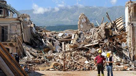 Zwei Feuerwehrleute stehen in den Trümmern der Stadt L'Aquila, die im Frühjahr 2009 von einem Erdbeben getroffen wurde. 
