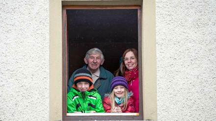 Bewohner eines Mehrgenerationenhauses schauen aus einem Fenster.