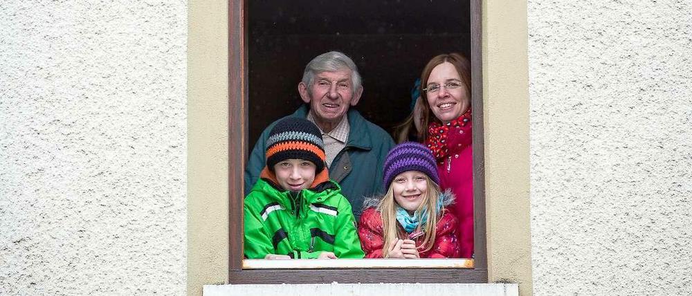 Bewohner eines Mehrgenerationenhauses schauen aus einem Fenster.