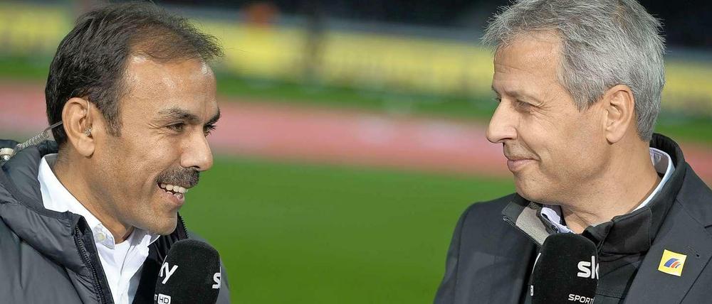 Jos Luhukay und Lucien Favre stehen nebeneinander mit Mikrofonen in der Hand.
