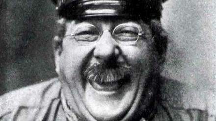 Das lachende Gesicht des Komödianten Henry Bender, der in der Rolle des Dienstmannes Max Pinne 1909 eine Schirmmütze trägt.