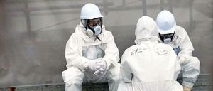 Krebsvorsorge am Reaktor: Eingehüllt in Schutzkleidung, machen Männer eine Pause von den Aufräumarbeiten am Kraftwerk in Fukushima.