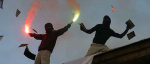 Berlin-Kreuzberg.  Teilnehmer einer "Revolutionären 1.-Mai-Demonstration stehen auf einem Dach und begleiten den Aufzug mit bengalischen Fackeln und Flugblättern.