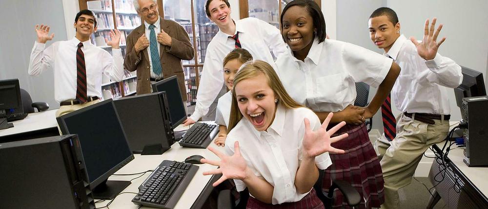 Schülerinnen und Schüler in Schuluniformen winken wild in die Kamera und werfen sich mit erhobenen Händen nach hinten.