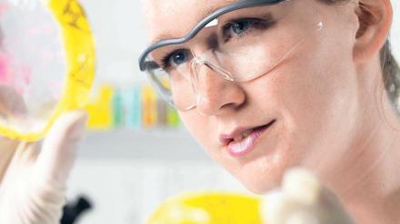 Eine Molekularbiologin mit Schutzbrille begutachtet eine Probe.