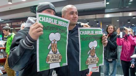 Kenny Rebenstock (links) und Nico Hirte haben am Samstagmorgen am Hauptbahnhof die einzigen beiden Ausgaben des französischen Satiremagazins Charlie Hebdo gekauft. Sie hatten seit Mitternacht vor der Buchhandlung gestanden.
