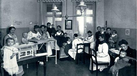 Das Behandlungszimmer für Säuglinge im Charlottenburger Pestalozzi-Fröbel-Haus: Zu sehen sind Mütter mit ihren Babys und medizinisches Personal.