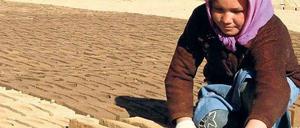 Ein Mädchen in Afghanistan arbeitet in einer Lehmziegelfabrik.