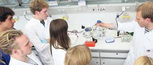 Studierende stehen in einem Labor um einen wissenschaftlichen Mitarbeiter herum.