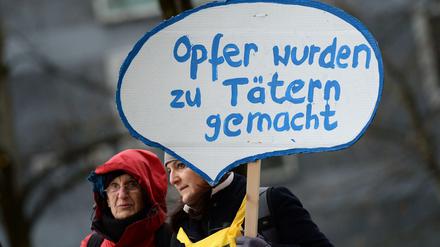 Mitglieder der Initiative «Keupstraße ist überall» stehen vor dem Oberlandesgericht in München und halten ein Schild mit der Aufschrift «Opfer wurden zu Tätern gemacht» in die Höhe.