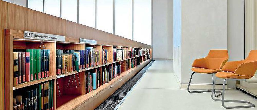 Zwei Lehre Stühle stehen in einem Bibliotheksraum auf einem leicht erhöhten Podium.