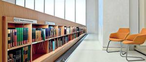 Zwei Lehre Stühle stehen in einem Bibliotheksraum auf einem leicht erhöhten Podium.