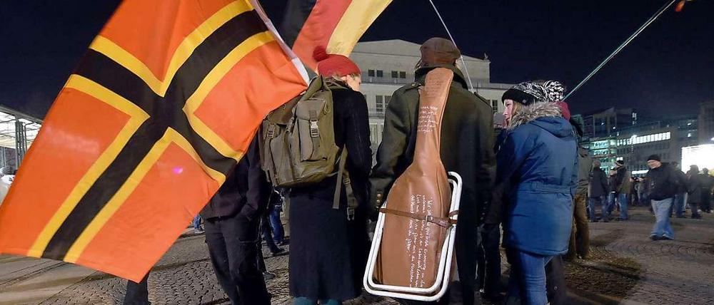 Legida-Teilnehmer ("Leipzig gegen die Islamisierung des Abendlandes") ziehen mit einer Flagge, die im Jahr 1944 von Josef Wirmer als Nationalflagge vorgeschlagen wurde, und einer Deutschlandfahne durch Leipzig. 