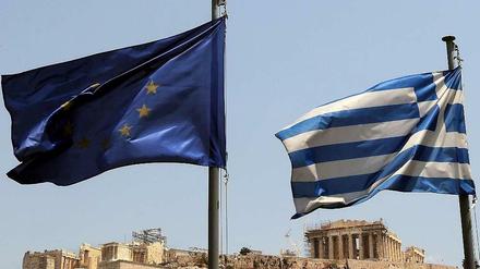 Die EU- und die griechische Flagge vor der Akropolis.