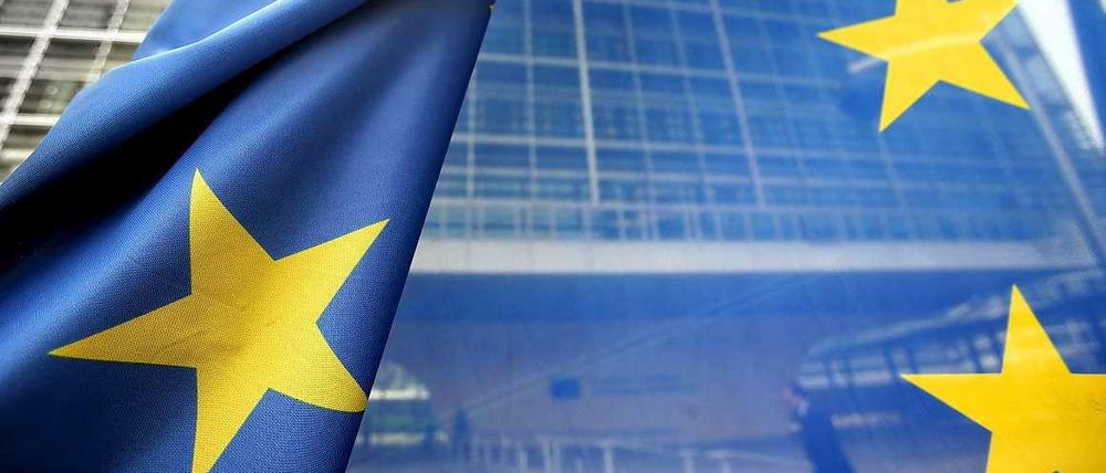 Und sie leuchten doch: Europas Sterne auf einer Flagge, im Hintergrund die Europäische Kommission in Brüssel.