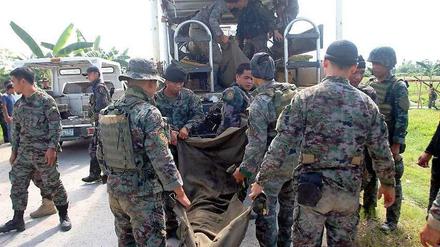 Polizisten einer philippinischen Eliteeinheit tragen einen von Rebellen getöteten Kameraden in den Mannschaftswagen. 