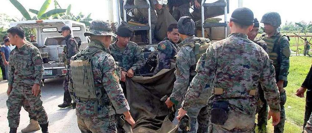Polizisten einer philippinischen Eliteeinheit tragen einen von Rebellen getöteten Kameraden in den Mannschaftswagen.