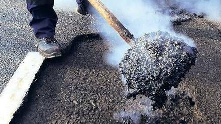 Dampf im Kessel. Ein Bauarbeiter füllt ein Schlagloch mit heißem Teer. Insgesamt ist der Sanierungsstau in Berlin so groß, dass viele Bezirke die Geschwindigkeit auf Hauptverkehrsstraßen drosseln, um Straßen und Fahrzeuge zu schonen. 