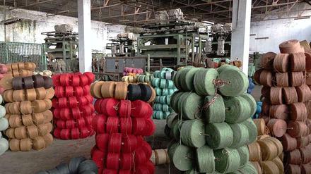 Eine alte Fabrik in Bangladesch, in der sich Türme aus buntem Jutegarn befinden