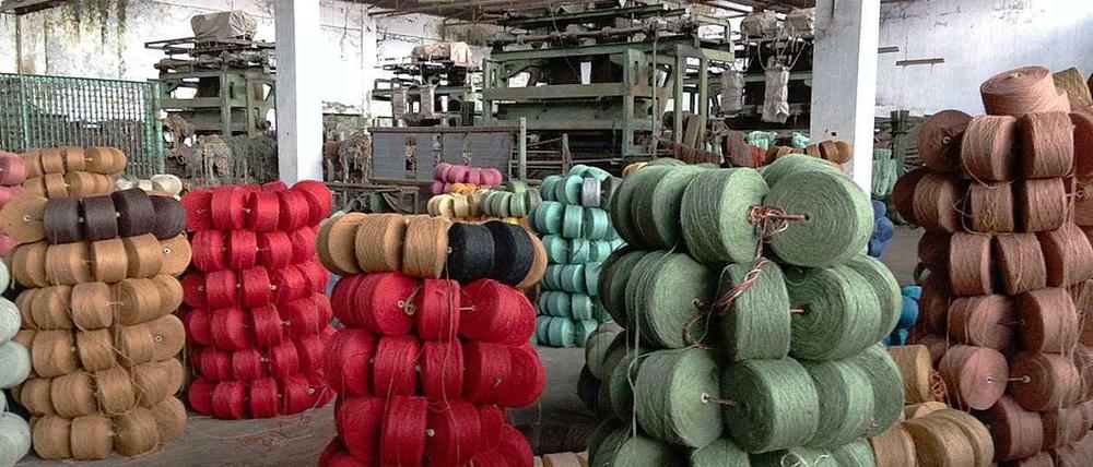 Eine alte Fabrik in Bangladesch, in der sich Türme aus buntem Jutegarn befinden