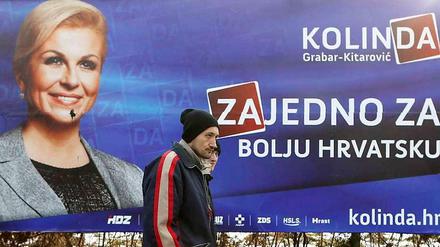 Zwei Kroaten in Zagreb (Archiv). Gehören sie zu den "Glücklichen", denen die Schulden von der Regierung erlassen werden? Im Hintergrund ein Wahlplakat der aktuellen Präsidentin Kroatiens, Kolinda Grabar Kitarovic.