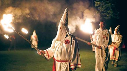 Zeremonie mit weißen Kutten und Spitzhauben. Die Bekleidung hatte der Ku-Klux-Klan Ende des 19. Jahrhunderts gewählt, um abergläubische Schwarze zu erschrecken.