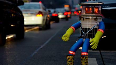 Hitchbot ist in Deutschland und sitzt am Straßenrand.