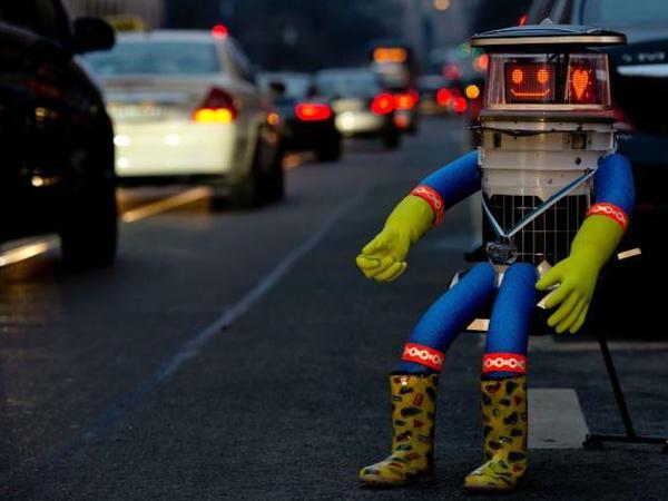 Hitchbot ist in Deutschland und sitzt am Straßenrand.