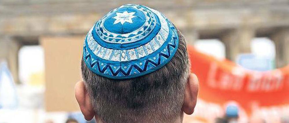 Ein jüdischer Mann mit Kippa vor dem Brandenburger Tor in Berlin.