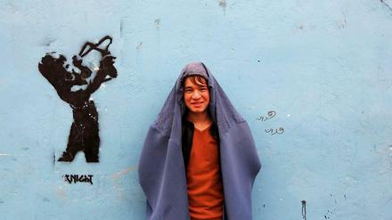 Ein Demonstranten in Kabul posiert vor einer Wand mit Graffiti. Anlässlich des bevorstehenden Weltfrauentags trugen Männer Burkas und liefen durch die Hauptstadt von Afghanistan. Mit der Aktion wollten sie ihre Solidarität zu den Frauen in ihrem Land zeigen. 