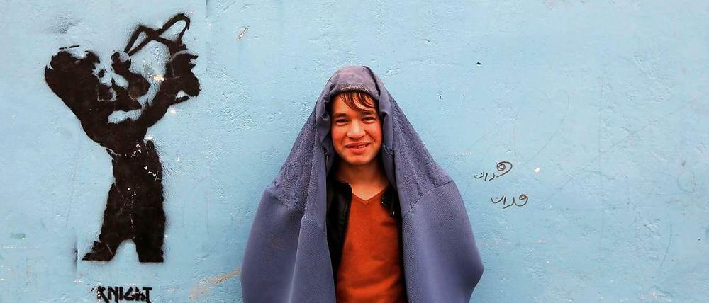 Ein Demonstranten in Kabul posiert vor einer Wand mit Graffiti. Anlässlich des bevorstehenden Weltfrauentags trugen Männer Burkas und liefen durch die Hauptstadt von Afghanistan. Mit der Aktion wollten sie ihre Solidarität zu den Frauen in ihrem Land zeigen. 