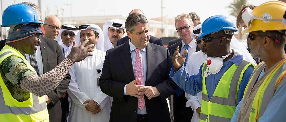 Bundeswirtschaftsminister Sigmar Gabriel (SPD) unterhält sich bei der Besichtigung des Urbanisierungsprojekts Lusail City in Doha (Katar) mit Bauarbeitern aus Ghana. 