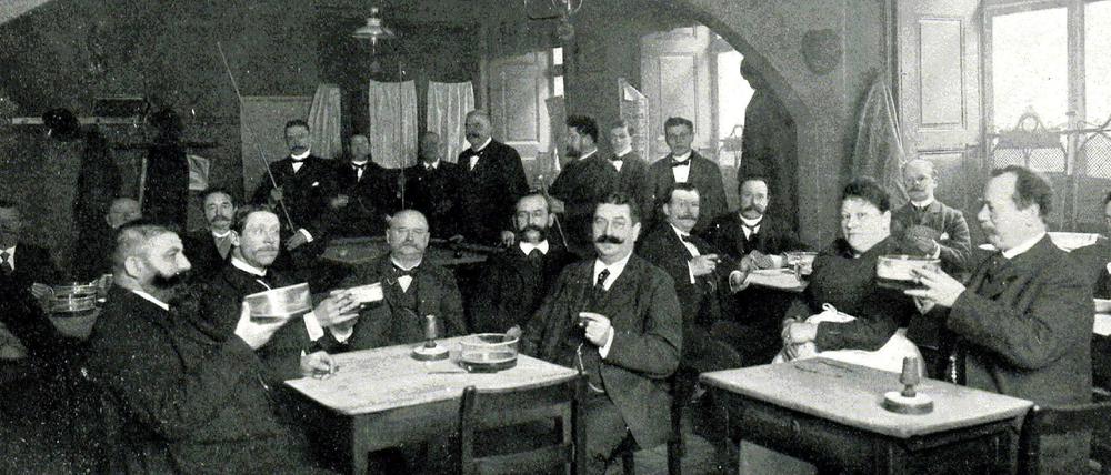 Altberliner Art. Berliner Weiße wird 1903 aus flachen Trinkgefäßen mit einem Umfang von Suppenschüsseln getrunken. Die Gäste der Weißbierstube haben mit dem Biergenuss alle Hände voll zu tun.
