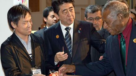 Auf der UN-Weltkonferenz zur Reduzierung der Risiken durch Naturkatastrophen im japanischen Sindai bietet der Premierminister von Japan, Shinzo Abe (m), dem Präsidenten von Vanuatu, Baldwin Lonsdale (r), eine Erdbeere an.