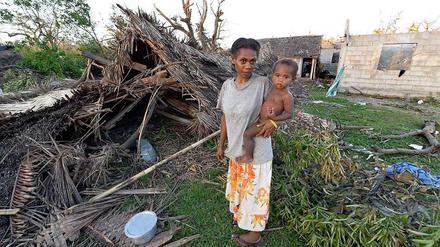 Mutter und Kind vor einer zerstörten Hütte auf Vanuatu. 