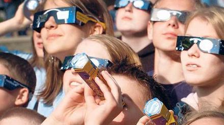 Nur mit Spezialbrille! Der ungeschützte Blick in die Sonne kann die Augen schwer schädigen. Richtig ausgerüstet können Beobachter sich aber auf das Spektakel freuen. Foto: Kay Nietfeld/dpa