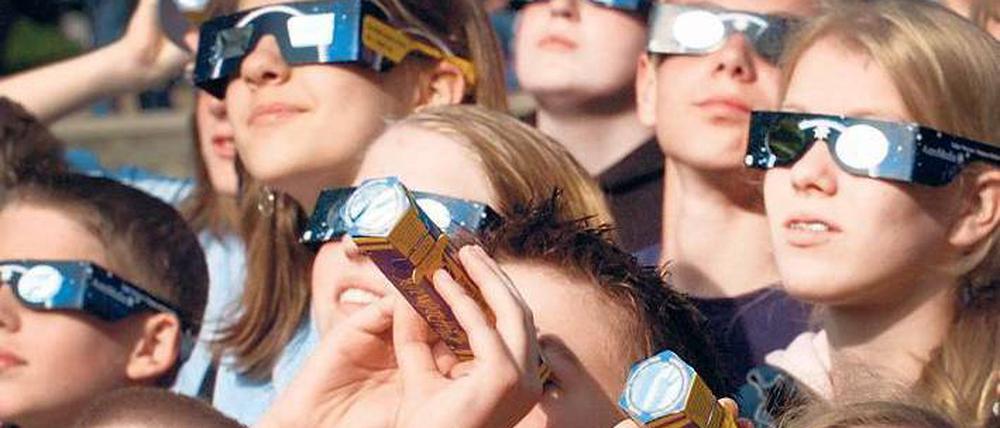 Nur mit Spezialbrille! Der ungeschützte Blick in die Sonne kann die Augen schwer schädigen. Richtig ausgerüstet können Beobachter sich aber auf das Spektakel freuen. Foto: Kay Nietfeld/dpa