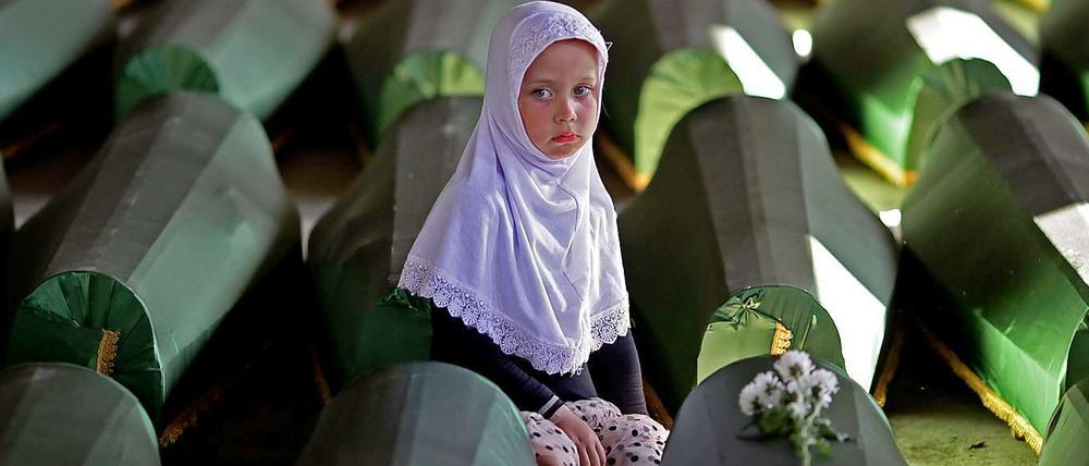 Ein Mädchen sitzt im Potocari Memorial Center an einem der 173 Särge mit Opfern aus Srebrenica, die zuletzt identifiziert worden waren.